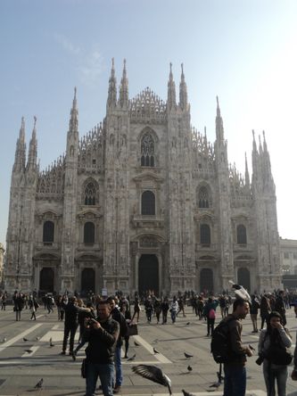 Piazza del Doumo. Flittigt besøgt af mennesker og duer. Domkirken i baggrunden. Byggeriet af kirken påbegyndt i 1386. Først afsluttet midt i 1800-tallet.