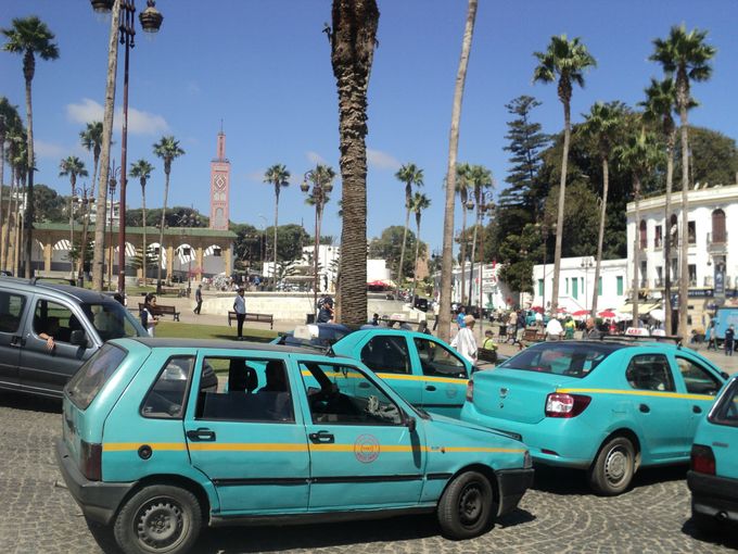 Taxaer i rundkørslen på Grand Socco. Den centrale plads er indgang til Medinaen og det fantastiske Cinémathéque de Tanger ﻿ligger på Grand Socco. I baggrunden til venstre Sidi Bou Abid Moskéen fra 1917. 