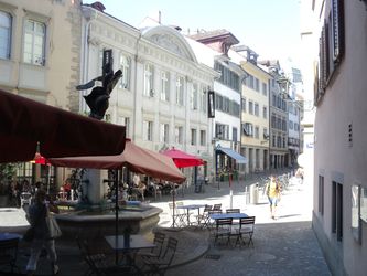 Den pittoreske gade Neumarkt. Ved Restaurant og café Kantorei. Den gamle bydel i Zürich. Et godt stop for en kaffe på en sommerdag. Fortovsbetjeningen på caféen er placeret omkring en fontæne. Fontæner er typiske for gadebilledet i Zürich.