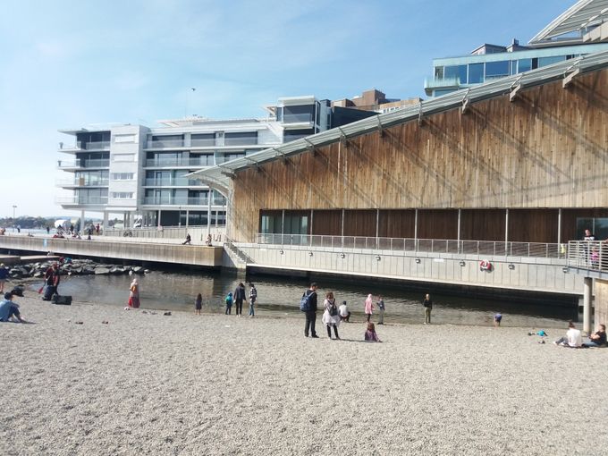 Astrup Fearnley Museet. Og foran dette et etableret badested komplet med sandstrand. Bagerst boliger for det formodede økonomisk bedre stillede befolkningslag i Oslo.
Altsammen på Tjuvholmen.